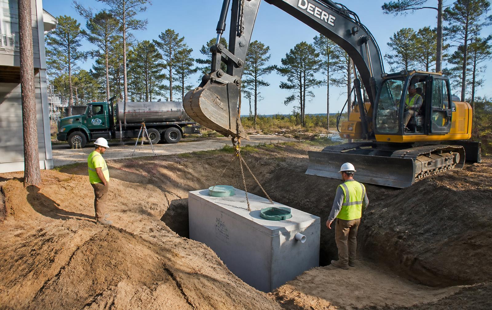Burch's Septic crew lowering a new concrete septic tank into a trench at an Onslow County home